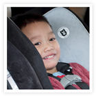 A smiling five-year-old in a car seat. 