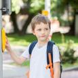 Little boy waits at street corner to cross the street