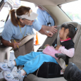 A car seat safety technician inspects a child in their car seat. 