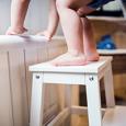 A toddler climbs a stool. 
