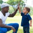 A Father give his smiling boy a high five.  