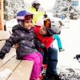 little girl getting ready to ski with her mom and family with the proper equipment