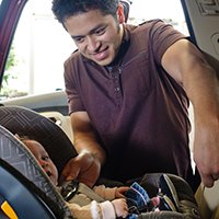 Father putting infant into car seat Father putting infant into car seat