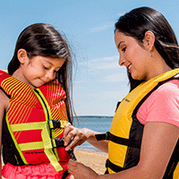 A mother fits a life jacket on her daughter. 