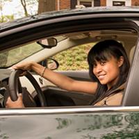 teen driving safety A teenage girl seat behind the steering wheel.