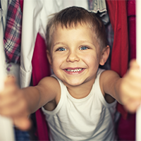 A young boy looking through his closet. 
