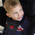 A smiling child buckled into his car seat. 