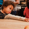 A toddler reaches of an object.