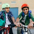 Two kids pose happily on their bikes with colorful helmets.  