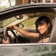 A teenage girl seat behind the steering wheel.  