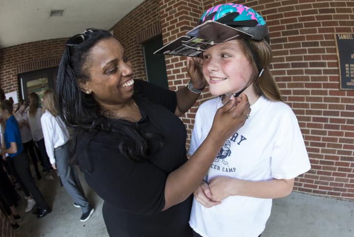 Torine Creppy, Safe Kids Interim President, helping a student fit a new bike helmet.